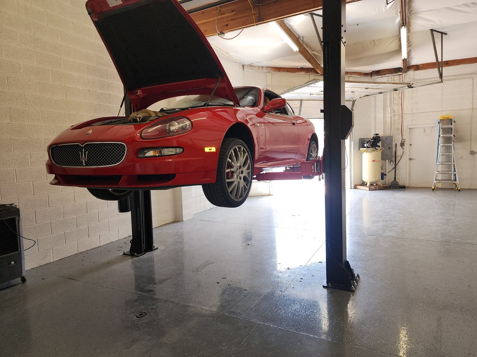 Maserati raised on a service lift inside the shop